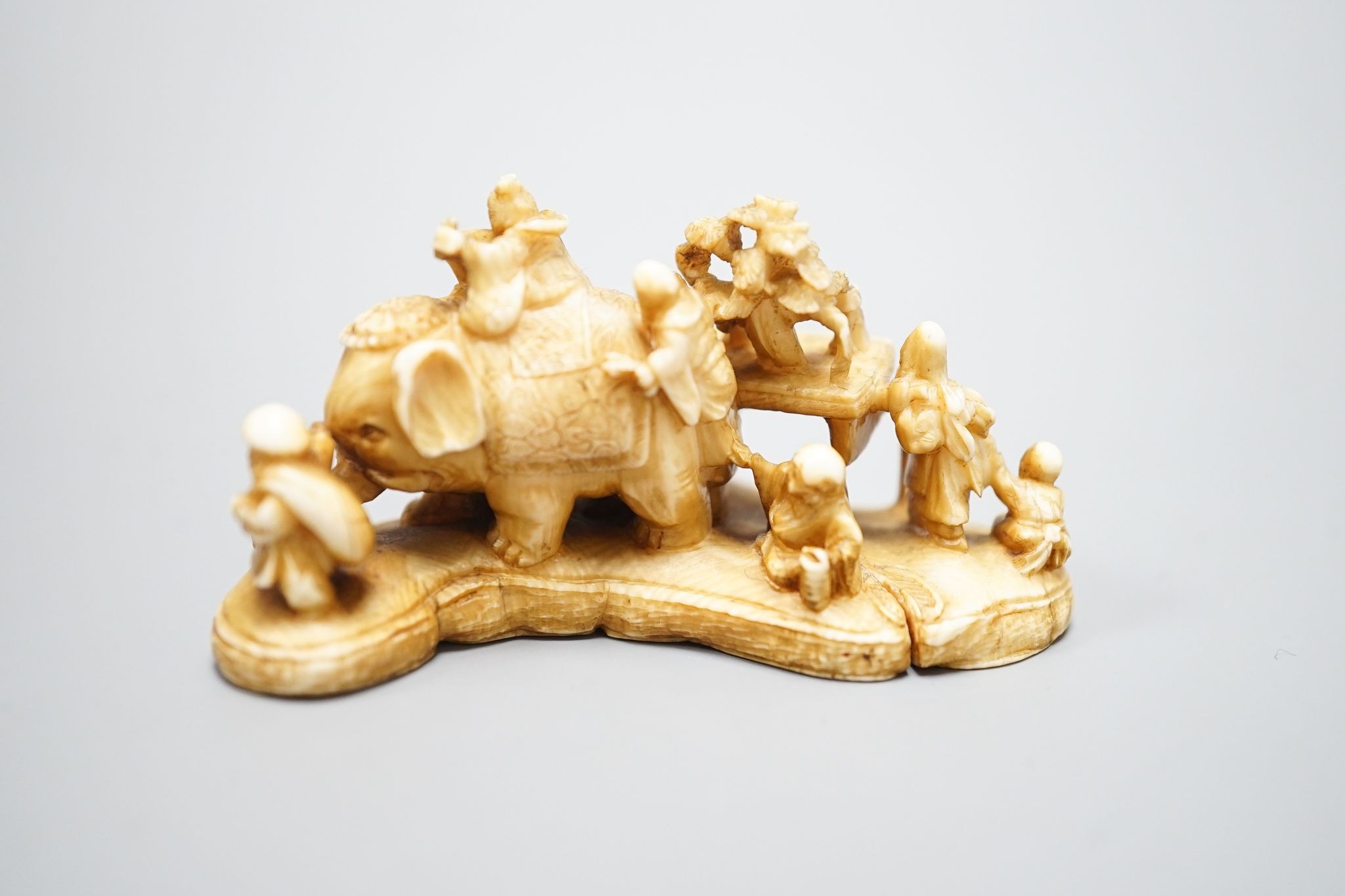 A Japanese carved ivory netsuke, mother of pearl inset to base with signature 'Gyokuzan', Meiji period, 6cm wide